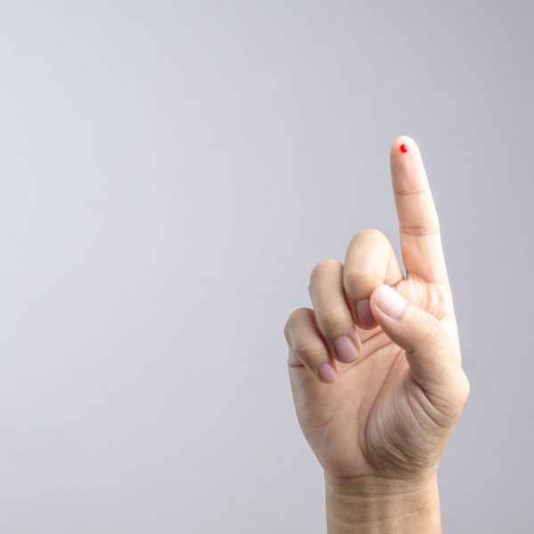 Hand with blood drop at finger from needle for sample testing on white background