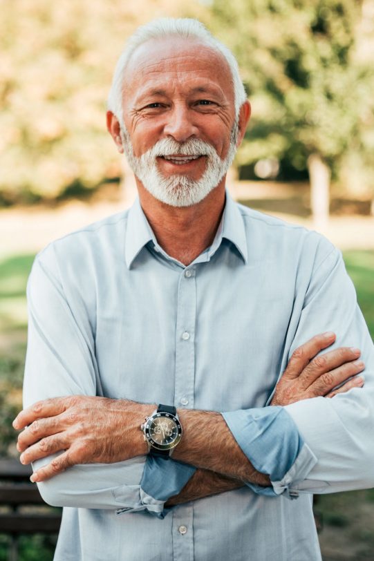 Portrait of a smiling older man in the park.